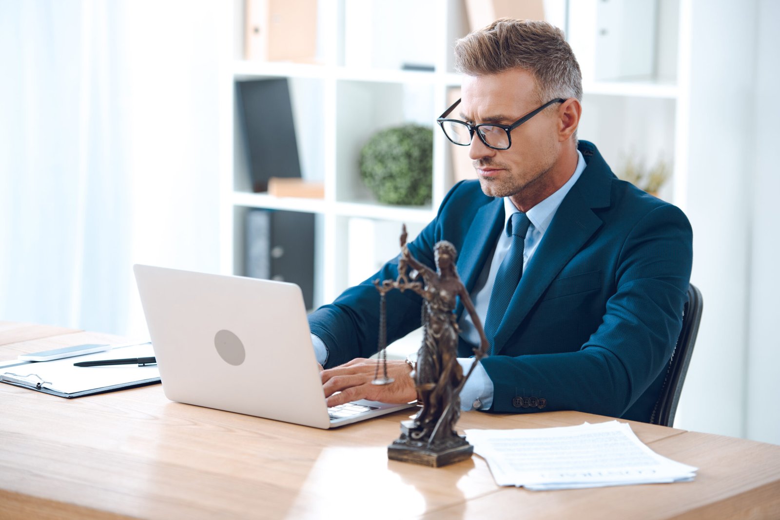 Asesor legal con lentes trabajando con computadora portatil